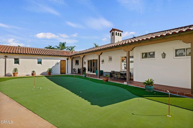 back of house featuring stucco siding, a tile roof, and a patio
