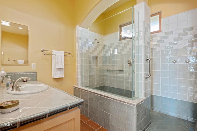 full bathroom with tile patterned flooring, tiled shower, and vanity