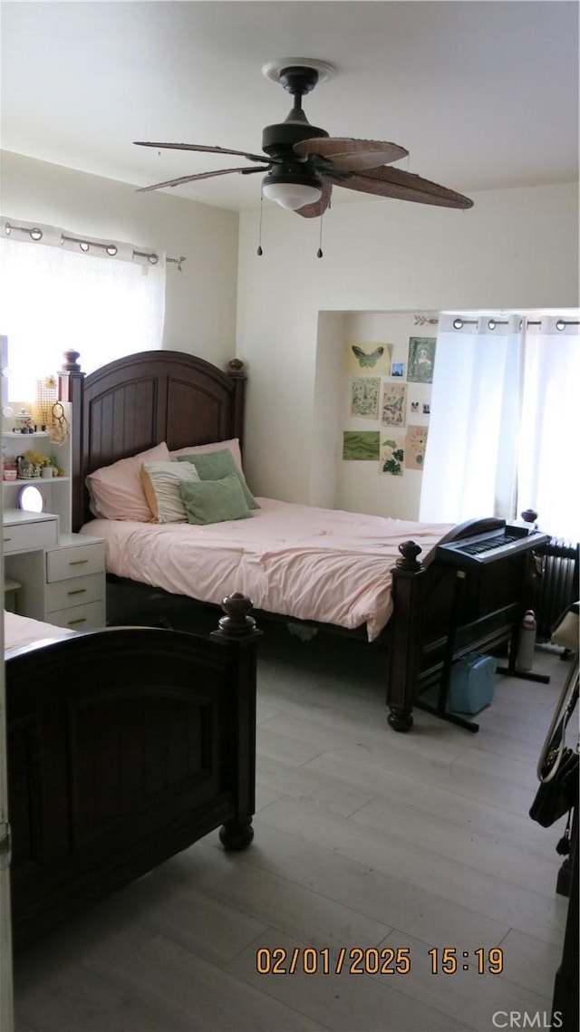 bedroom featuring multiple windows, ceiling fan, and light wood-type flooring