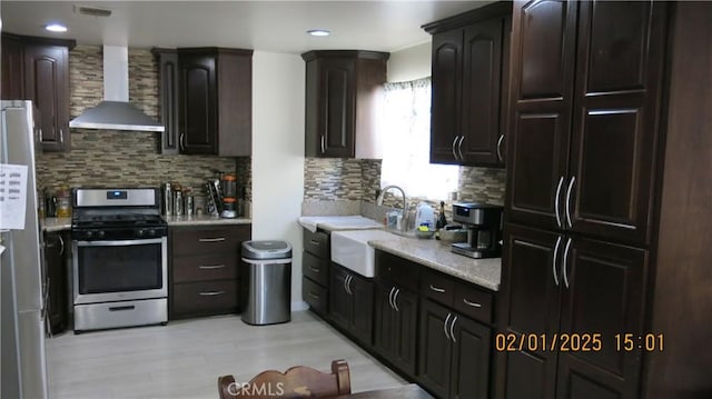 kitchen with tasteful backsplash, appliances with stainless steel finishes, sink, and wall chimney range hood