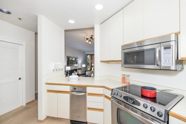 kitchen with stainless steel appliances, white cabinetry, light hardwood / wood-style flooring, and kitchen peninsula