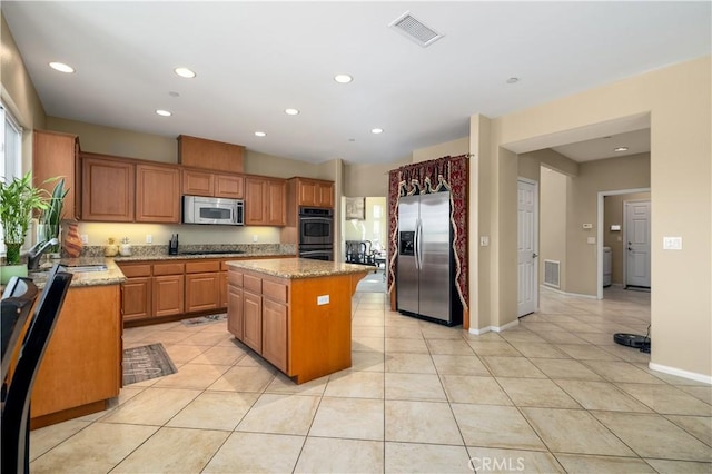 kitchen featuring light stone countertops, stainless steel appliances, sink, and a kitchen island