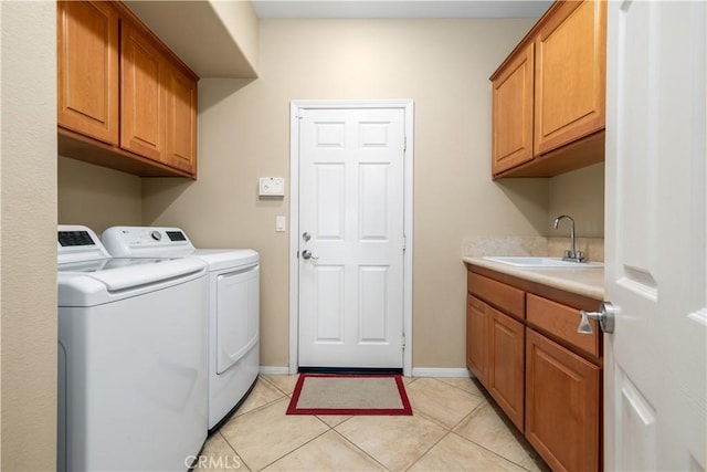 clothes washing area featuring light tile patterned flooring, cabinets, sink, and washer and dryer