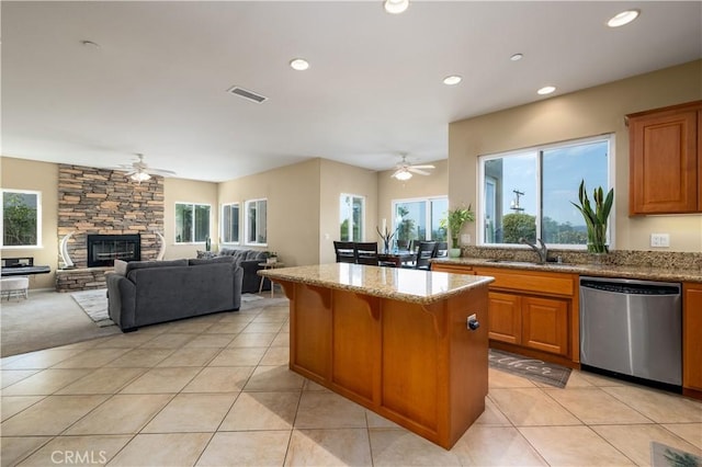 kitchen with stainless steel dishwasher, sink, a kitchen island, and a wealth of natural light