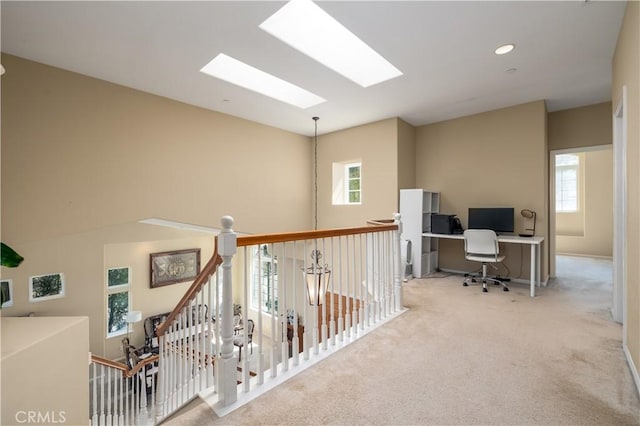 corridor featuring light colored carpet and a skylight