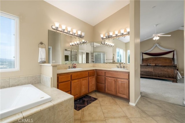 bathroom featuring vanity, tile patterned flooring, vaulted ceiling, and tiled bath