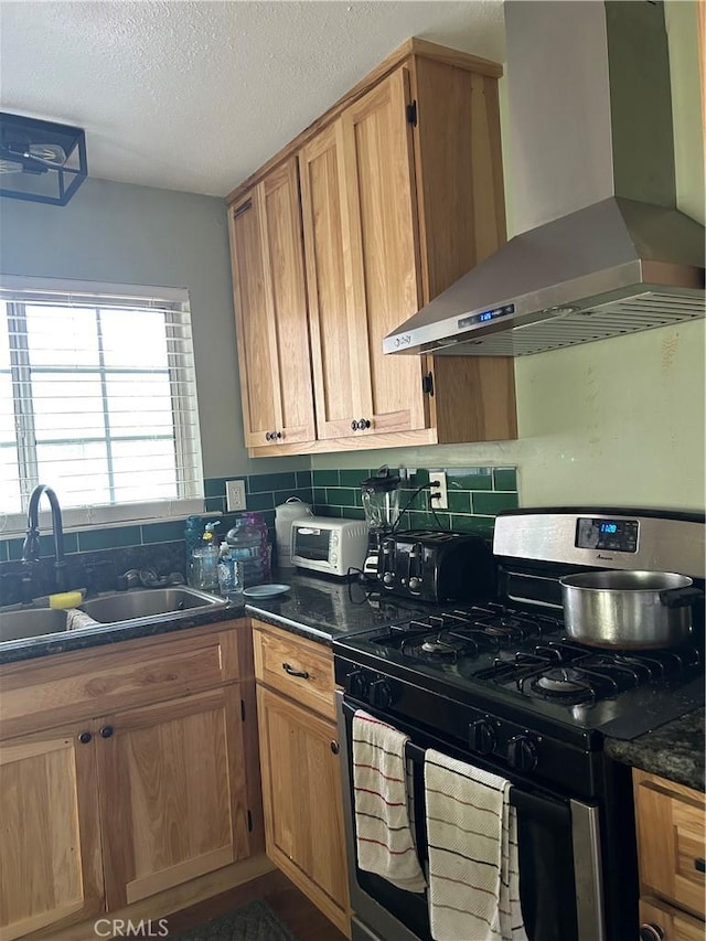 kitchen featuring tasteful backsplash, wall chimney exhaust hood, sink, and gas stove