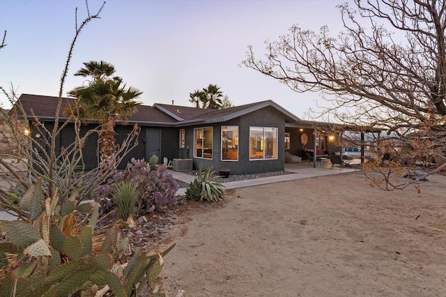 back house at dusk featuring a patio and central air condition unit