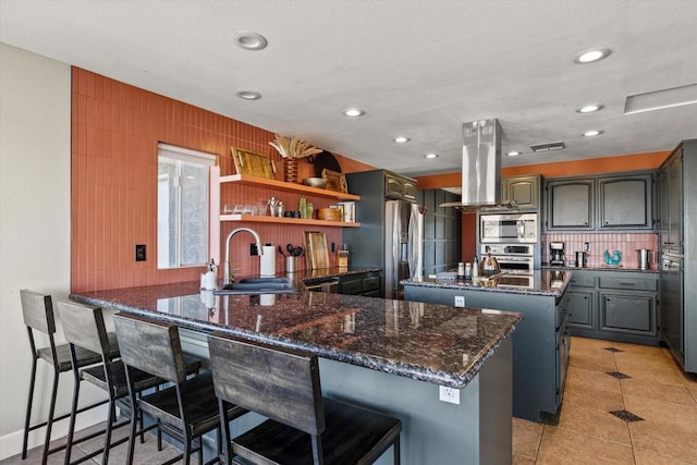 kitchen with appliances with stainless steel finishes, a kitchen breakfast bar, a center island, and sink