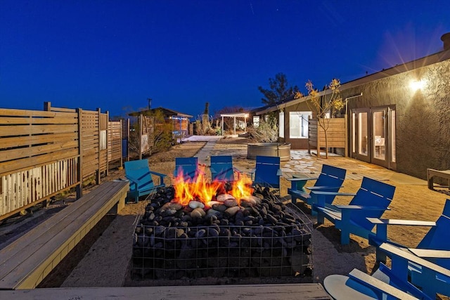 pool at twilight featuring a fire pit and french doors