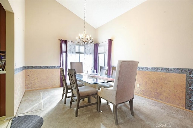 dining area featuring a chandelier, high vaulted ceiling, wainscoting, and carpet flooring