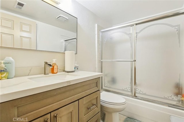 full bath with visible vents, shower / bath combination with glass door, vanity, and toilet