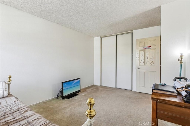 carpeted bedroom with a textured ceiling and a closet