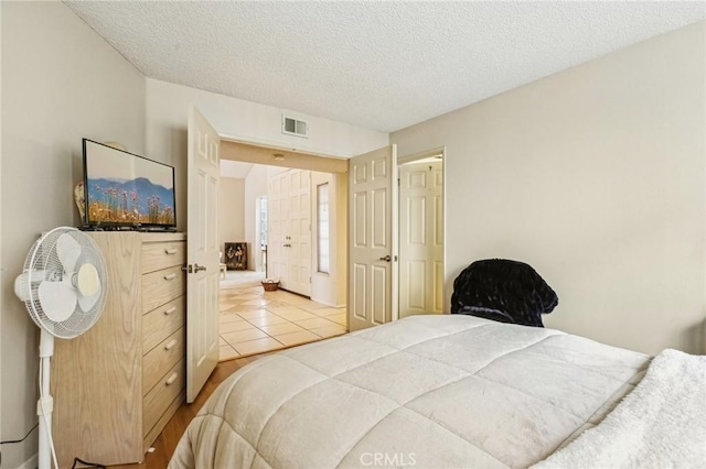 bedroom with visible vents, a textured ceiling, and tile patterned floors