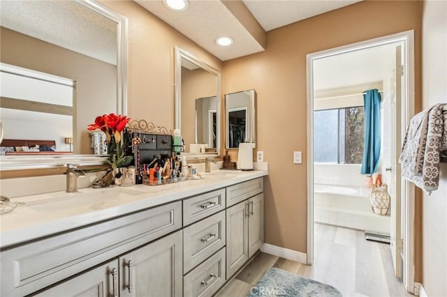 bathroom with double vanity, recessed lighting, a sink, and wood finished floors