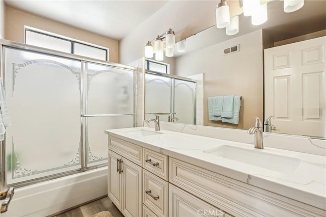 full bathroom featuring enclosed tub / shower combo, double vanity, a sink, and visible vents