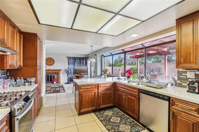 kitchen with light tile patterned floors, backsplash, appliances with stainless steel finishes, a sink, and light stone countertops