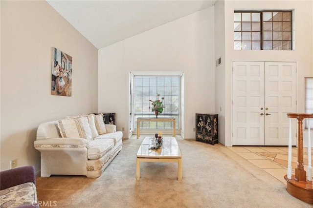 carpeted living area with visible vents, high vaulted ceiling, and tile patterned floors