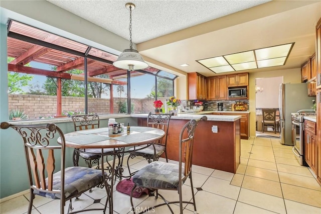 kitchen featuring stainless steel appliances, brown cabinetry, decorative backsplash, and light tile patterned flooring