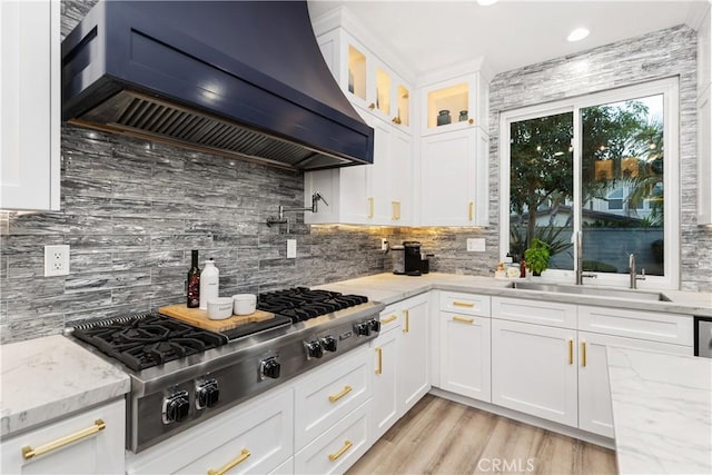 kitchen featuring premium range hood, light stone countertops, stainless steel gas cooktop, and white cabinets