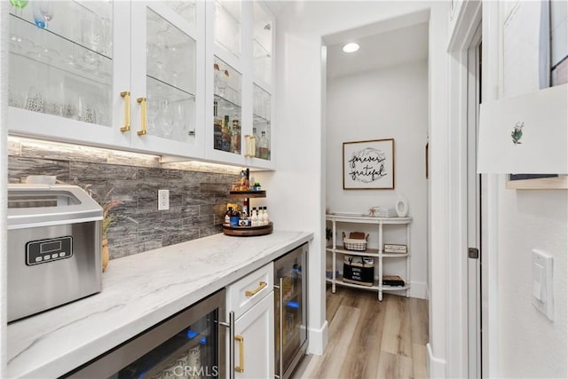 bar with white cabinets, tasteful backsplash, light stone countertops, and wine cooler