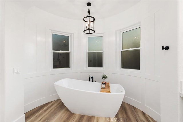 bathroom featuring an inviting chandelier, a bath, and hardwood / wood-style floors