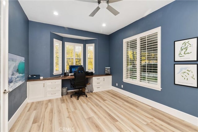 office area with built in desk, light hardwood / wood-style flooring, and ceiling fan