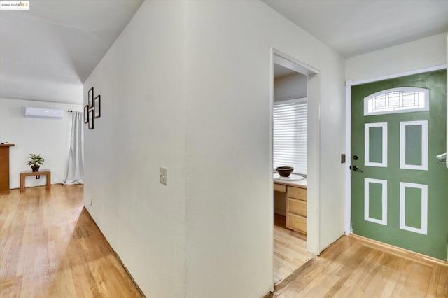 foyer entrance featuring hardwood / wood-style flooring and an AC wall unit