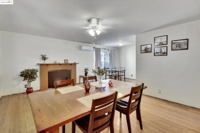 dining space with ceiling fan, light hardwood / wood-style floors, and a wall mounted AC