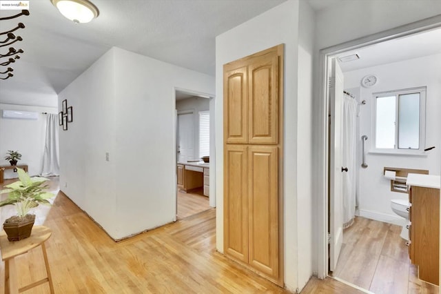 hall with a wall mounted AC and light wood-type flooring