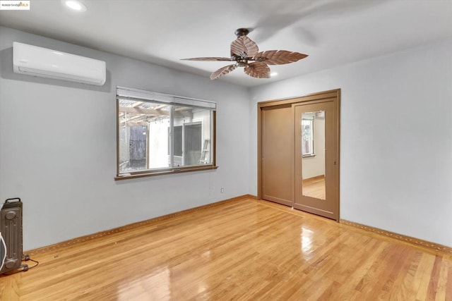 empty room with hardwood / wood-style flooring, an AC wall unit, and ceiling fan