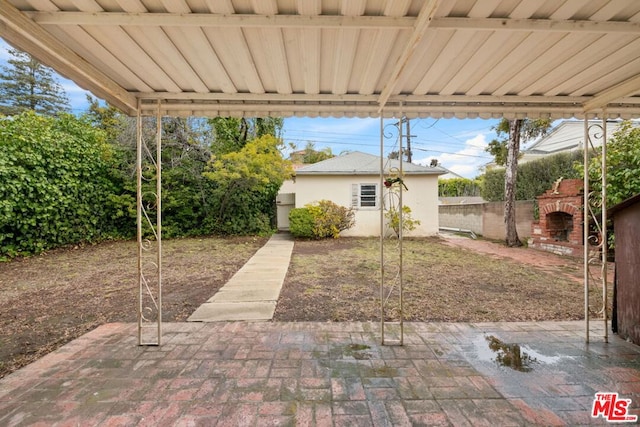 view of yard featuring an outdoor brick fireplace and a patio area