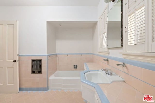 bathroom with sink, tile walls, tile patterned flooring, heating unit, and a bathing tub