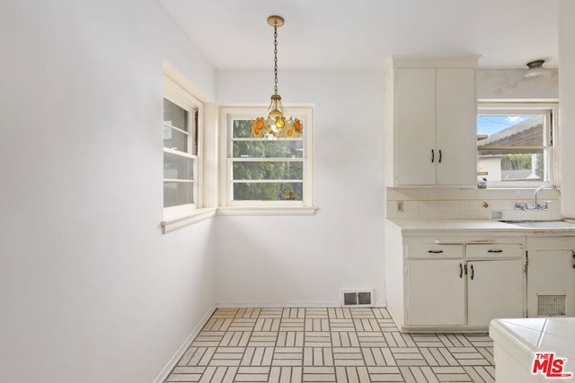 kitchen with pendant lighting, backsplash, sink, and white cabinets