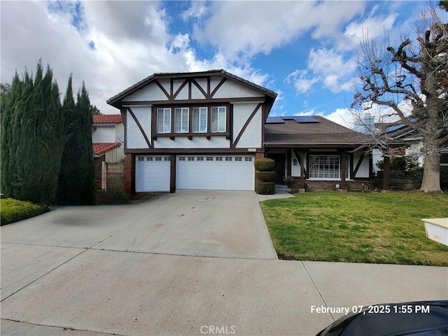 tudor-style house featuring a garage, driveway, roof mounted solar panels, a front lawn, and stucco siding