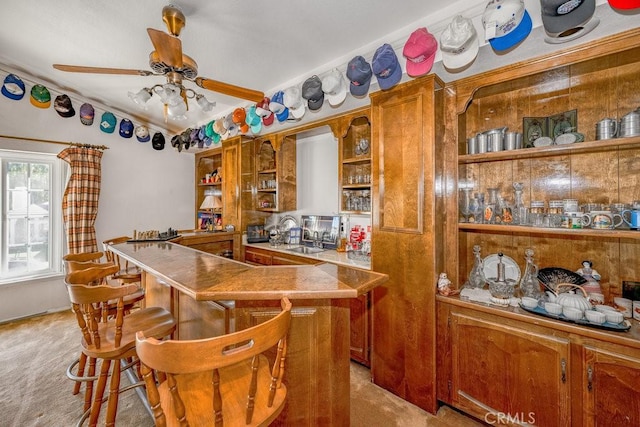 kitchen featuring a ceiling fan, brown cabinets, light colored carpet, and open shelves