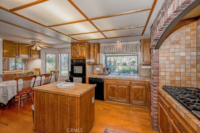 kitchen featuring a center island, a sink, light wood finished floors, and black appliances