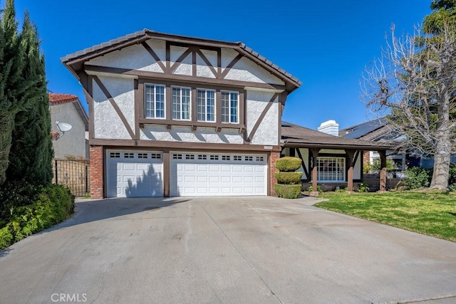 tudor house featuring a garage, driveway, stucco siding, a front yard, and brick siding