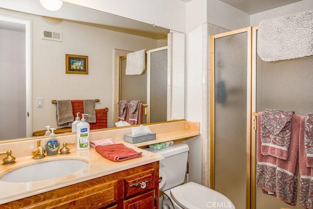 bathroom featuring toilet, a stall shower, vanity, and visible vents