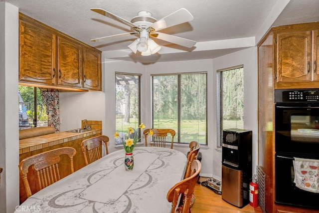 dining space with light wood-type flooring and a ceiling fan