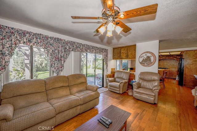 living room featuring ceiling fan, a textured ceiling, and wood finished floors