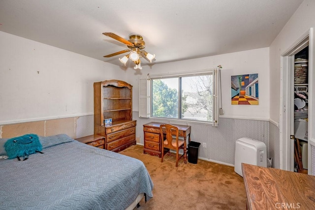 bedroom with ceiling fan, wainscoting, and light colored carpet