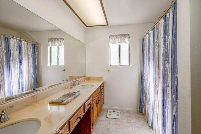 bathroom featuring double vanity, baseboards, a sink, and tile patterned floors