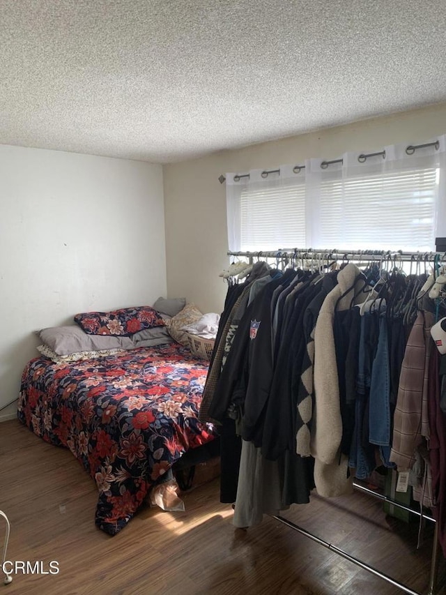 bedroom featuring a textured ceiling, multiple windows, and wood finished floors