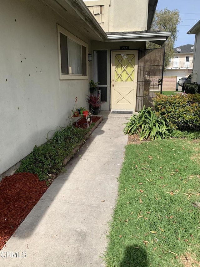 entrance to property featuring a lawn and stucco siding