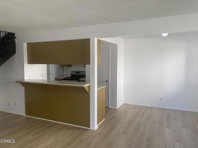 757 Halyard St, Port Hueneme, CA 93041 - kitchen with electric stove, light wood finished floors, a kitchen breakfast bar, a peninsula, and a textured ceiling