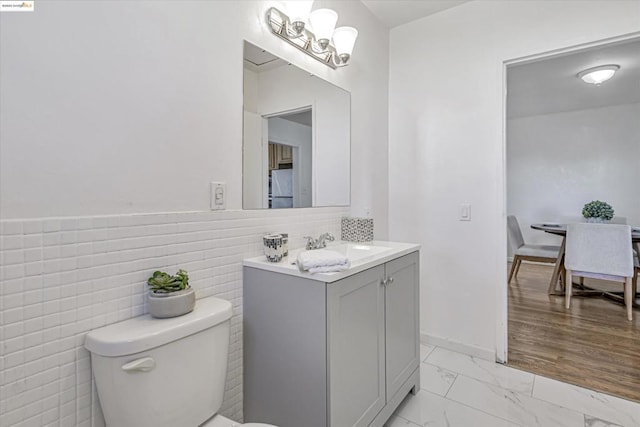 bathroom with vanity, tile walls, and toilet