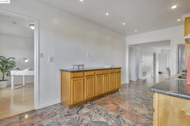 kitchen featuring dark stone counters, stainless steel fridge, and sink