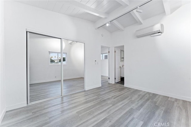 217 10th St, Seal Beach, CA 90740 - unfurnished bedroom featuring a wall mounted AC, track lighting, light wood-style flooring, a closet, and baseboards