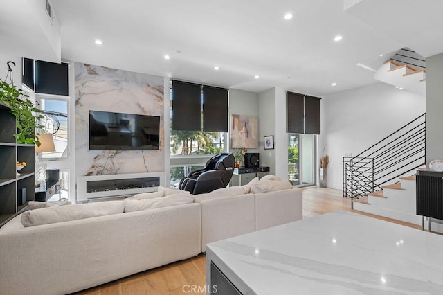 living area with stairway, recessed lighting, light wood finished floors, and a healthy amount of sunlight